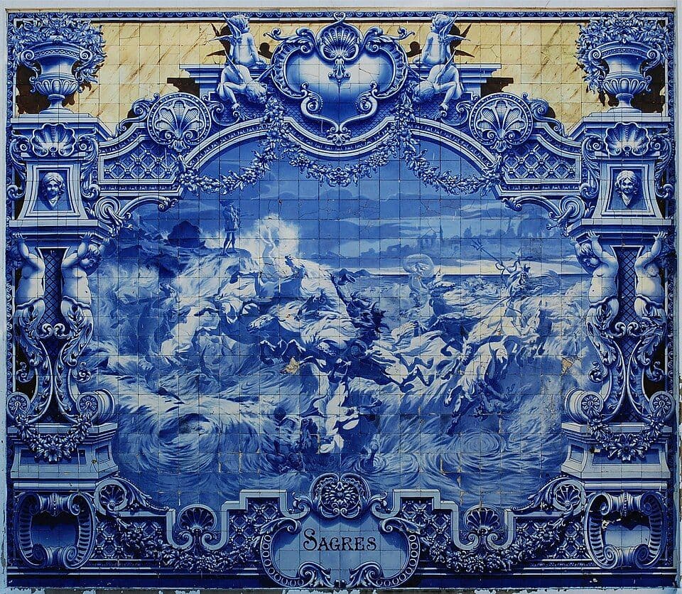 Painel de azulejos azuis e brancos com uma cena marítima emoldurada por ornamentos barrocos e a palavra Sagres