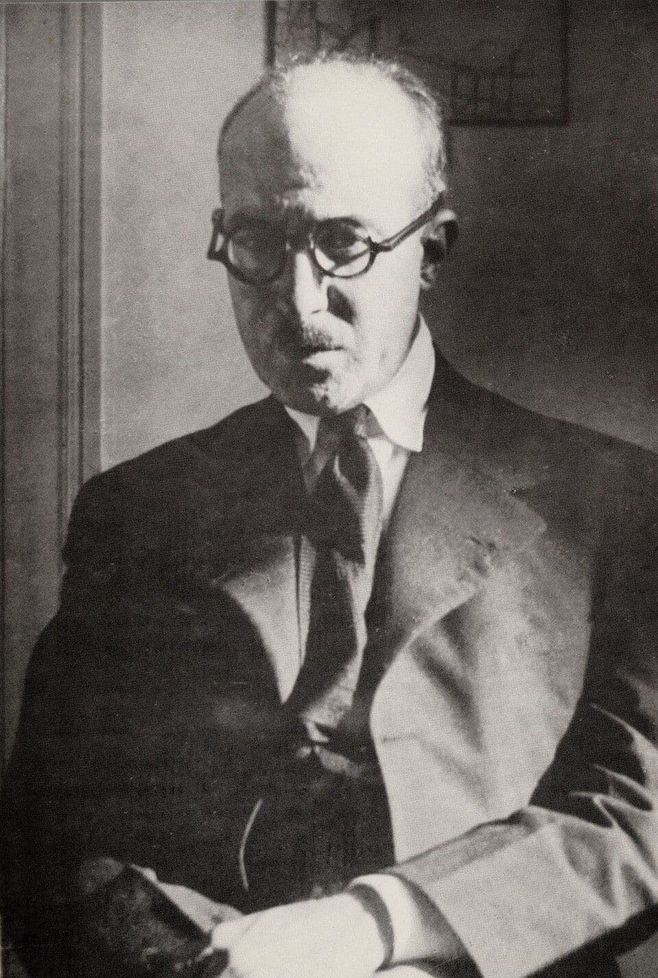 Fotografia a preto e branco de Fernando Pessoa de óculos redondos, fato e gravata
