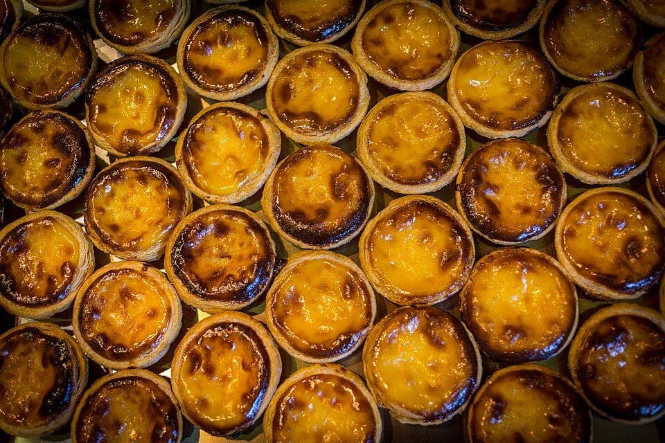 Tabuleiro cheio de pastéis de nata acabados de cozer, vistos de cima