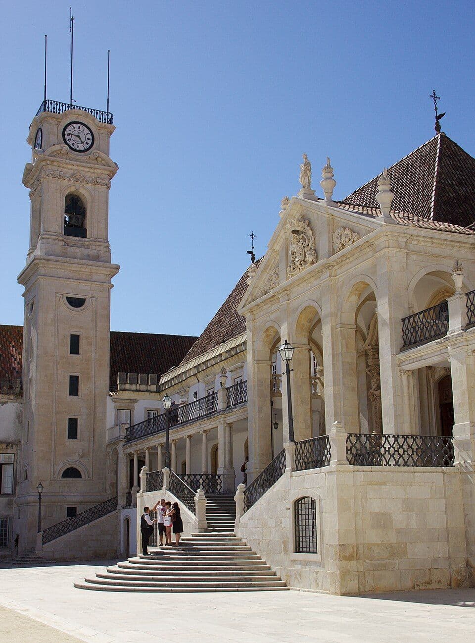 Torre do relógio da Universidade de Coimbra e a escadaria da Via Latina, sob céu azul