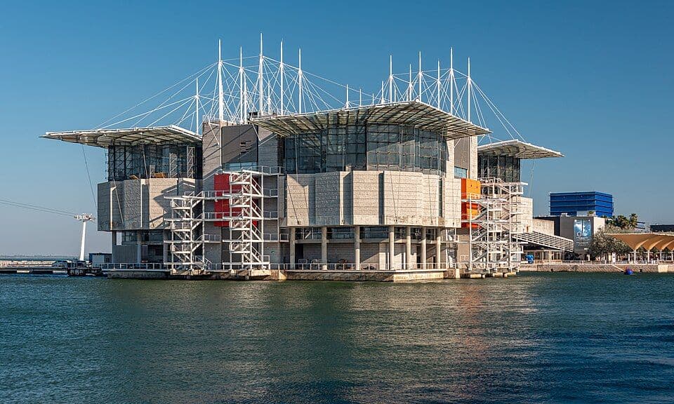Edifício do Oceanário de Lisboa, assente sobre a água, com mastros e cabos no telhado