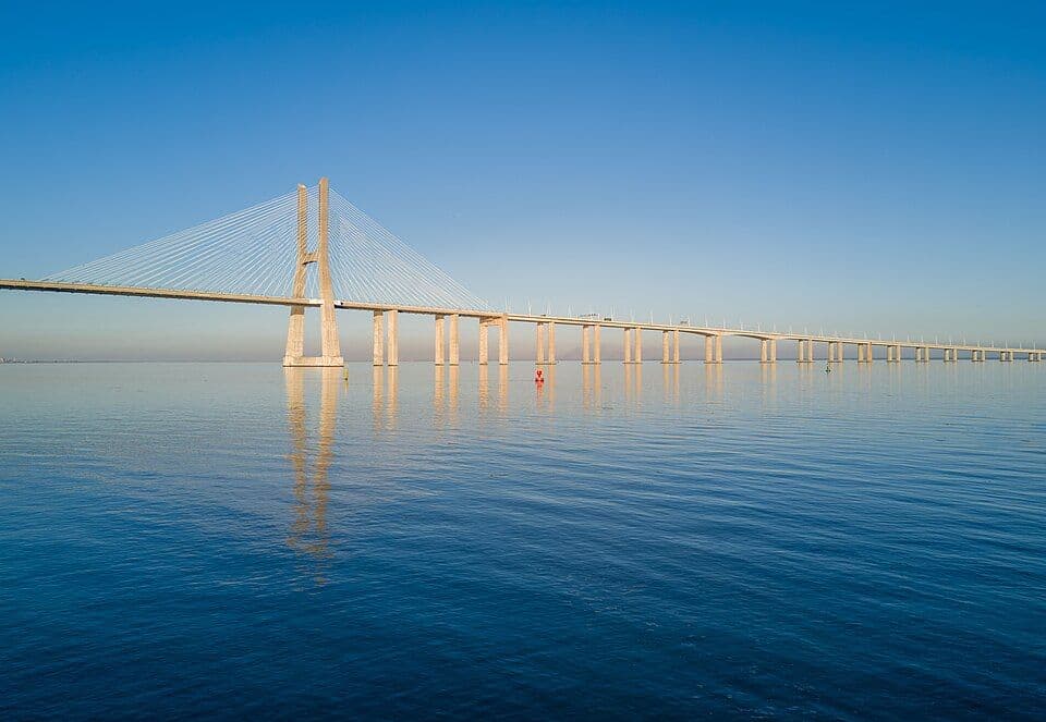 Ponte Vasco da Gama a atravessar o Tejo, refletida no rio calmo