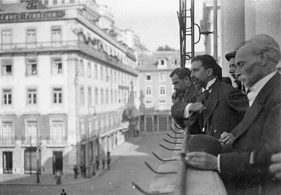 Fotografia a preto e branco de homens na varanda da Câmara Municipal de Lisboa, por cima da praça